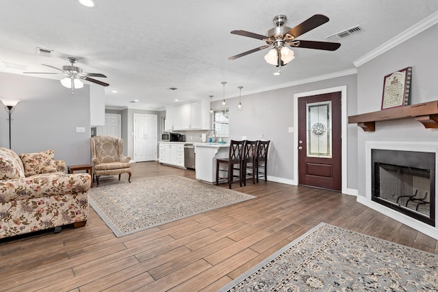 living area with dark wood-style floors, ornamental molding, visible vents, and baseboards