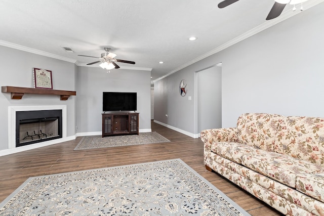 living area with baseboards, visible vents, ornamental molding, wood finished floors, and a fireplace