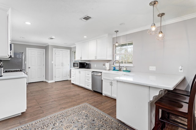 kitchen with ornamental molding, a peninsula, appliances with stainless steel finishes, and visible vents