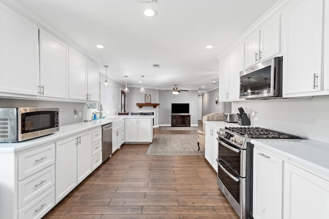 kitchen featuring stainless steel appliances, open floor plan, white cabinetry, ceiling fan, and a peninsula