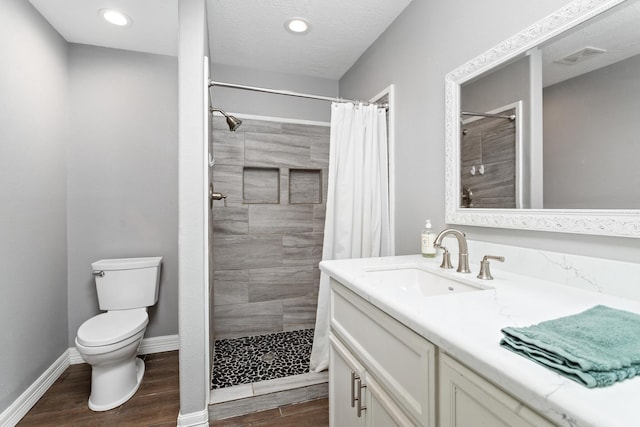 bathroom with tiled shower, wood finished floors, toilet, and baseboards