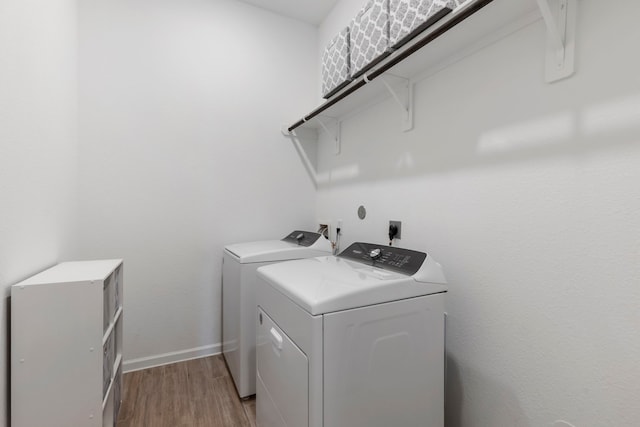 laundry area with baseboards, light wood-style flooring, laundry area, and washing machine and clothes dryer