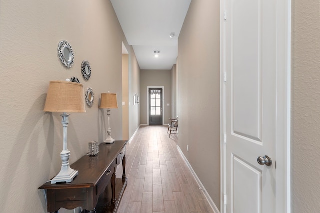 corridor with baseboards and wood finished floors