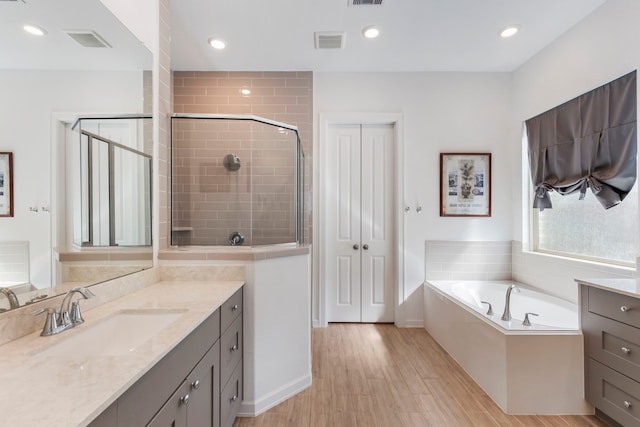 full bathroom with vanity, wood finished floors, visible vents, and a stall shower