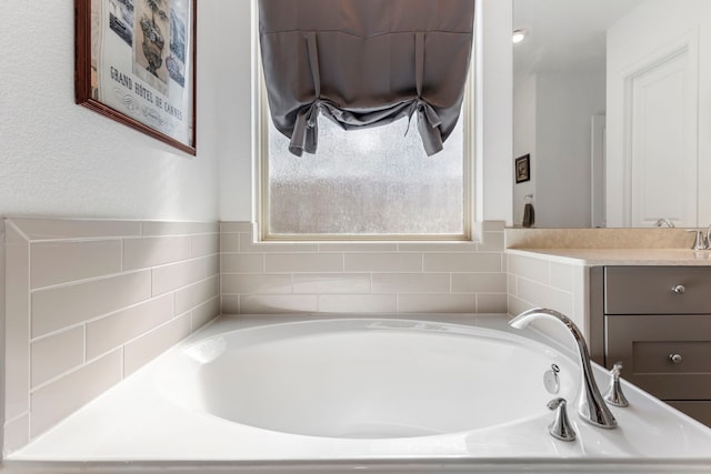 bathroom with a garden tub and vanity