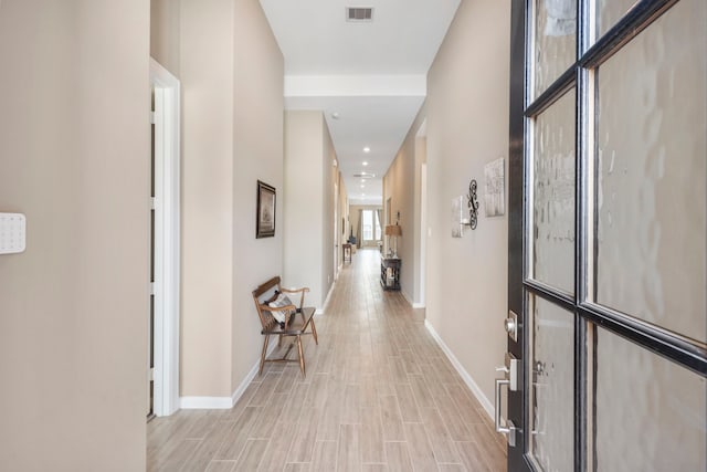 corridor featuring baseboards, visible vents, and light wood-type flooring