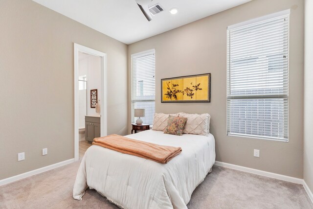 bedroom featuring visible vents, light colored carpet, connected bathroom, and baseboards