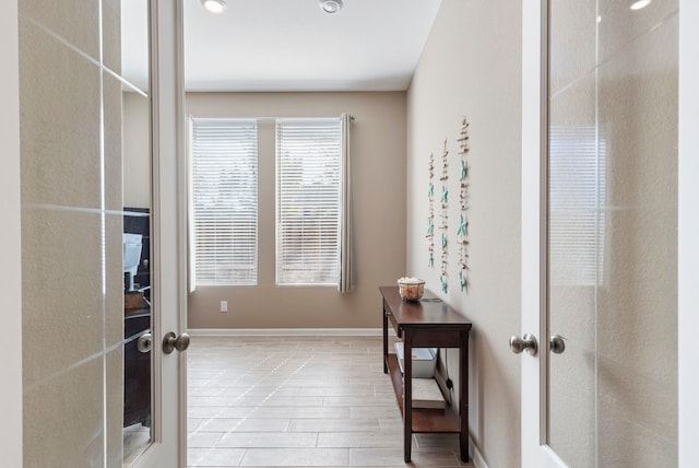 hall featuring wood finished floors, french doors, and baseboards