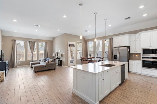 kitchen with a sink, visible vents, appliances with stainless steel finishes, and open floor plan