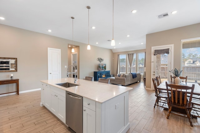 kitchen featuring stainless steel dishwasher, wood finish floors, white cabinets, and a sink