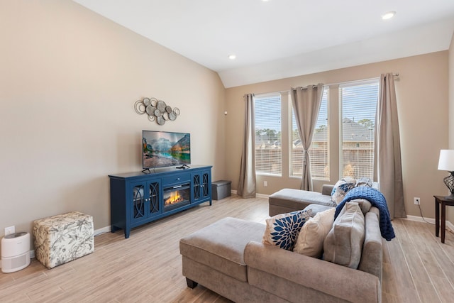 living room featuring lofted ceiling, light wood-style floors, and baseboards