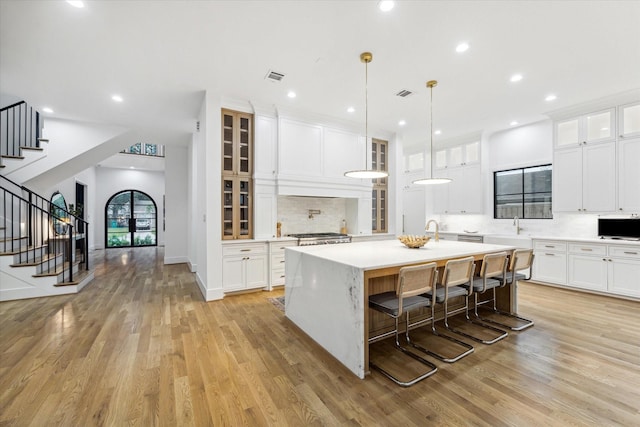 kitchen featuring white cabinetry, visible vents, light countertops, and a center island