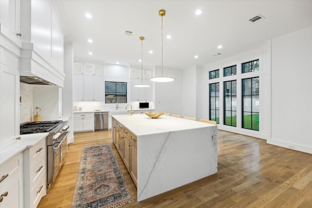 kitchen featuring visible vents, appliances with stainless steel finishes, a kitchen island with sink, light wood-type flooring, and recessed lighting