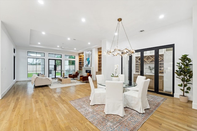 dining space featuring light wood-type flooring, a glass covered fireplace, baseboards, and recessed lighting