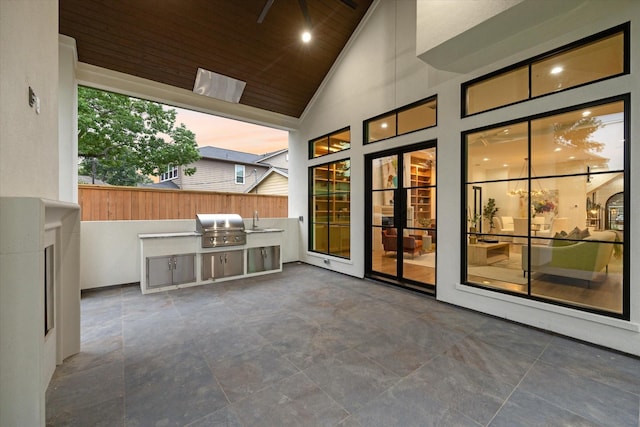 patio terrace at dusk featuring fence, grilling area, a sink, and area for grilling