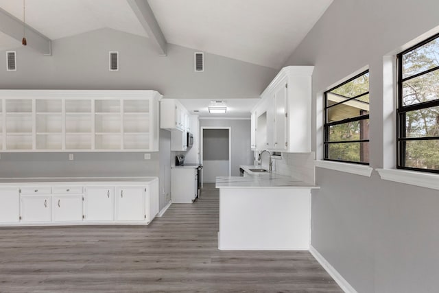 kitchen with vaulted ceiling with beams, light wood-style floors, range, and a sink