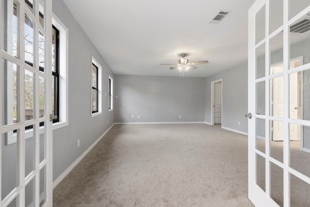 carpeted empty room with visible vents, french doors, a ceiling fan, and baseboards