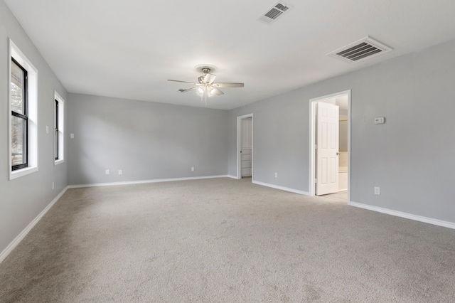 unfurnished room with light colored carpet, visible vents, ceiling fan, and baseboards