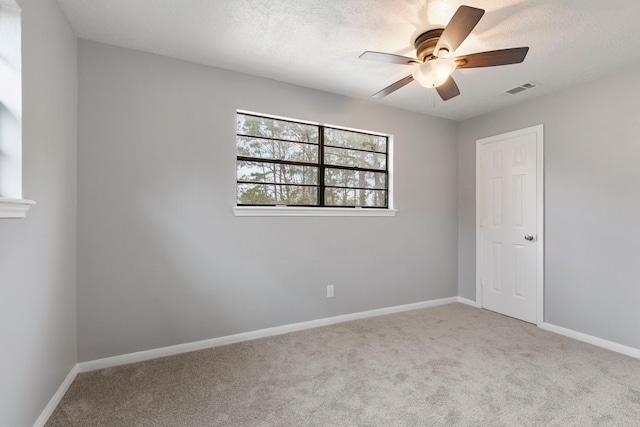 unfurnished room featuring a ceiling fan, carpet, visible vents, and baseboards