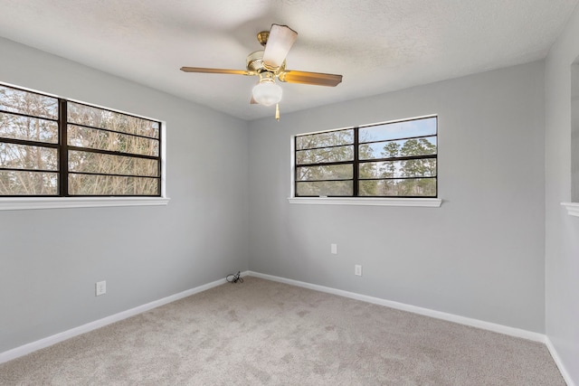 spare room with carpet floors, ceiling fan, a textured ceiling, and baseboards