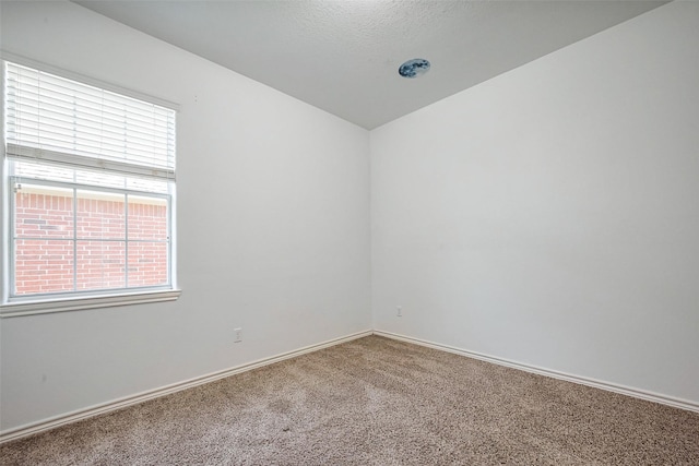 empty room featuring carpet and baseboards