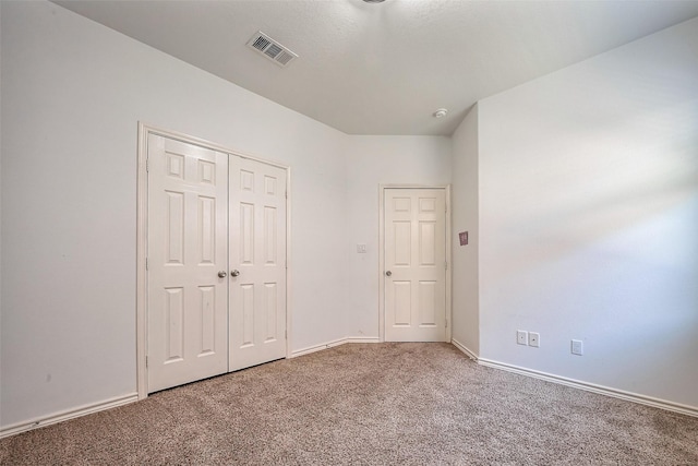 unfurnished bedroom with a closet, carpet flooring, visible vents, and baseboards