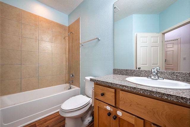 bathroom with shower / tub combination, toilet, wood finished floors, visible vents, and vanity