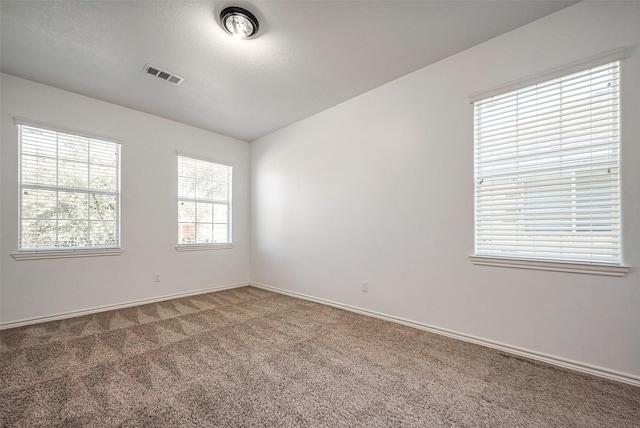 unfurnished room featuring baseboards, visible vents, a textured ceiling, and carpet flooring