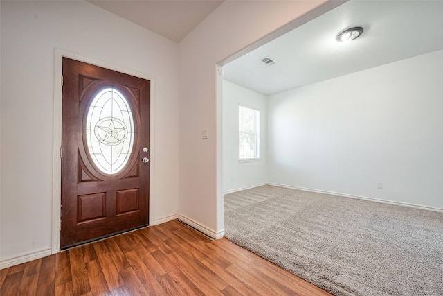 foyer entrance featuring visible vents, baseboards, and wood finished floors