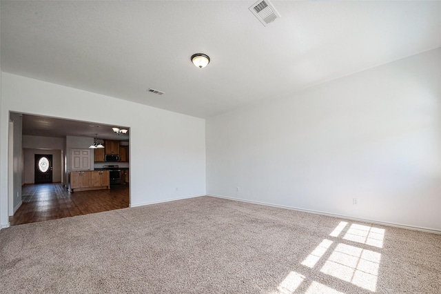 empty room with dark colored carpet, visible vents, and baseboards