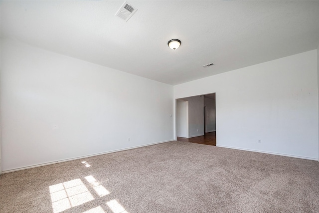 spare room featuring baseboards, visible vents, and dark carpet