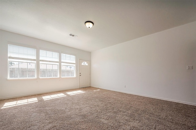 carpeted spare room with visible vents and baseboards