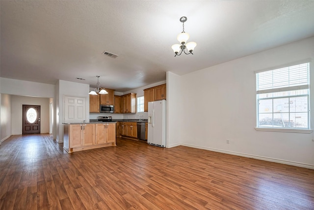 kitchen with dark wood-style floors, a notable chandelier, stainless steel appliances, visible vents, and open floor plan