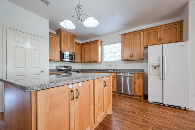 kitchen with a center island, hanging light fixtures, appliances with stainless steel finishes, dark wood-type flooring, and a sink