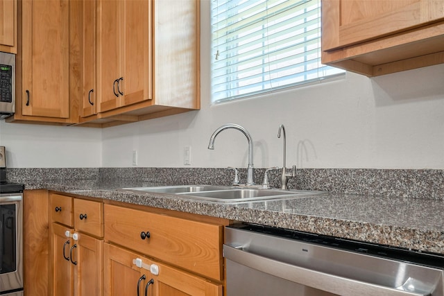 kitchen with stainless steel appliances, dark countertops, and a sink