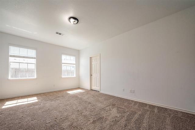 empty room featuring carpet floors, visible vents, and baseboards