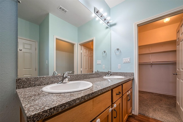 bathroom featuring double vanity, visible vents, a sink, and wood finished floors