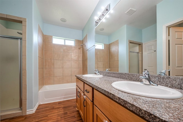 full bathroom with a shower with door, a sink, visible vents, and wood finished floors