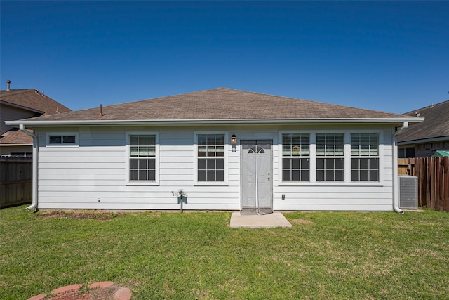 back of property with cooling unit, a yard, and fence