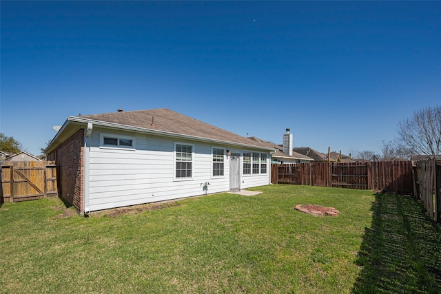 rear view of property featuring a fenced backyard, a lawn, and brick siding