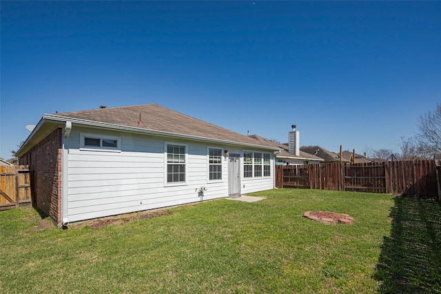 back of property with brick siding, a lawn, and a fenced backyard