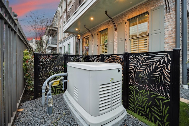 exterior details with fence, a power unit, and brick siding