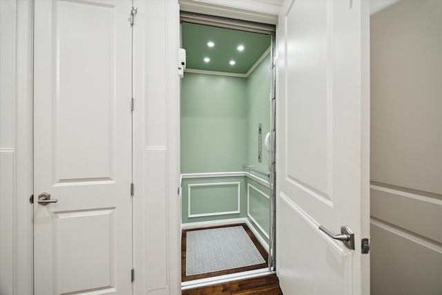 interior space featuring crown molding, recessed lighting, a decorative wall, wainscoting, and wood finished floors