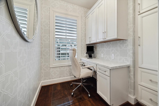 office space featuring baseboards, built in desk, dark wood finished floors, and wallpapered walls