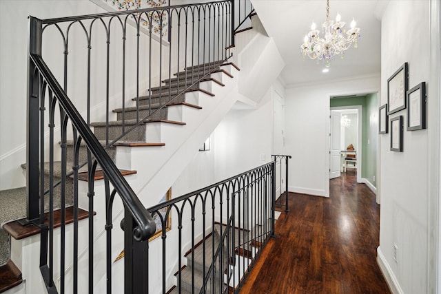 corridor with an inviting chandelier, crown molding, baseboards, and wood finished floors