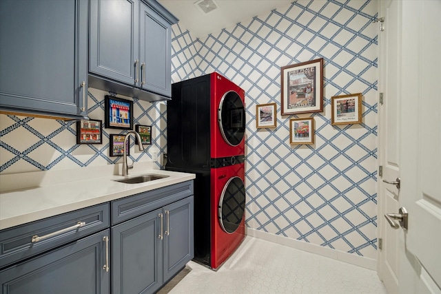 laundry area featuring a sink, visible vents, stacked washer and clothes dryer, and cabinet space