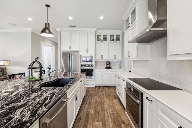 kitchen with visible vents, a sink, stainless steel appliances, wall chimney exhaust hood, and white cabinets