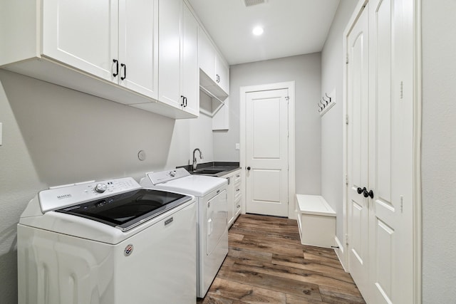 washroom with visible vents, washing machine and clothes dryer, cabinet space, dark wood-style flooring, and a sink