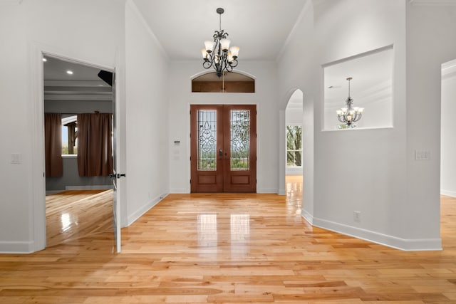 foyer entrance with a chandelier, baseboards, light wood-style flooring, and crown molding