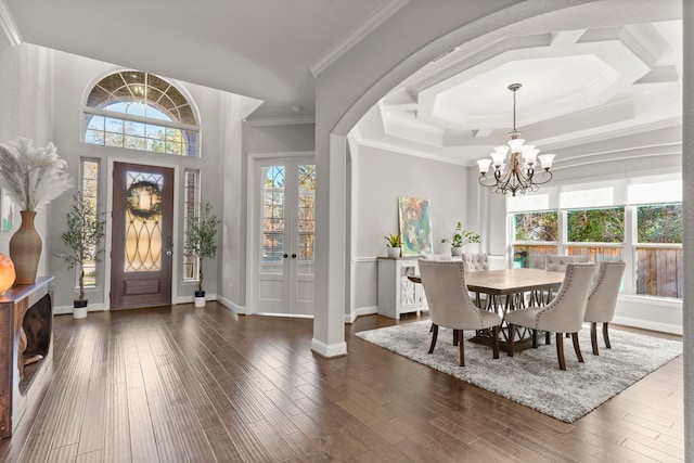 dining space with arched walkways, a notable chandelier, wood finished floors, baseboards, and crown molding